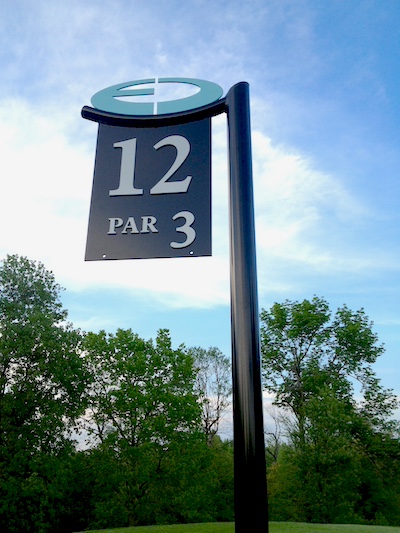 Layered metal tee sign with cut metal branding elements 